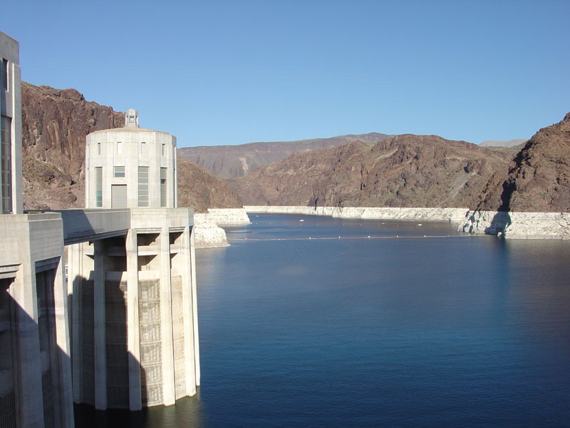 Lake Mead seen from Hoover Dam, with a water intake tower on the Nevada side at left: a white mineral bathtub ring runs along the canyon walls above the waterline, marking the level the reservoir used to stand at